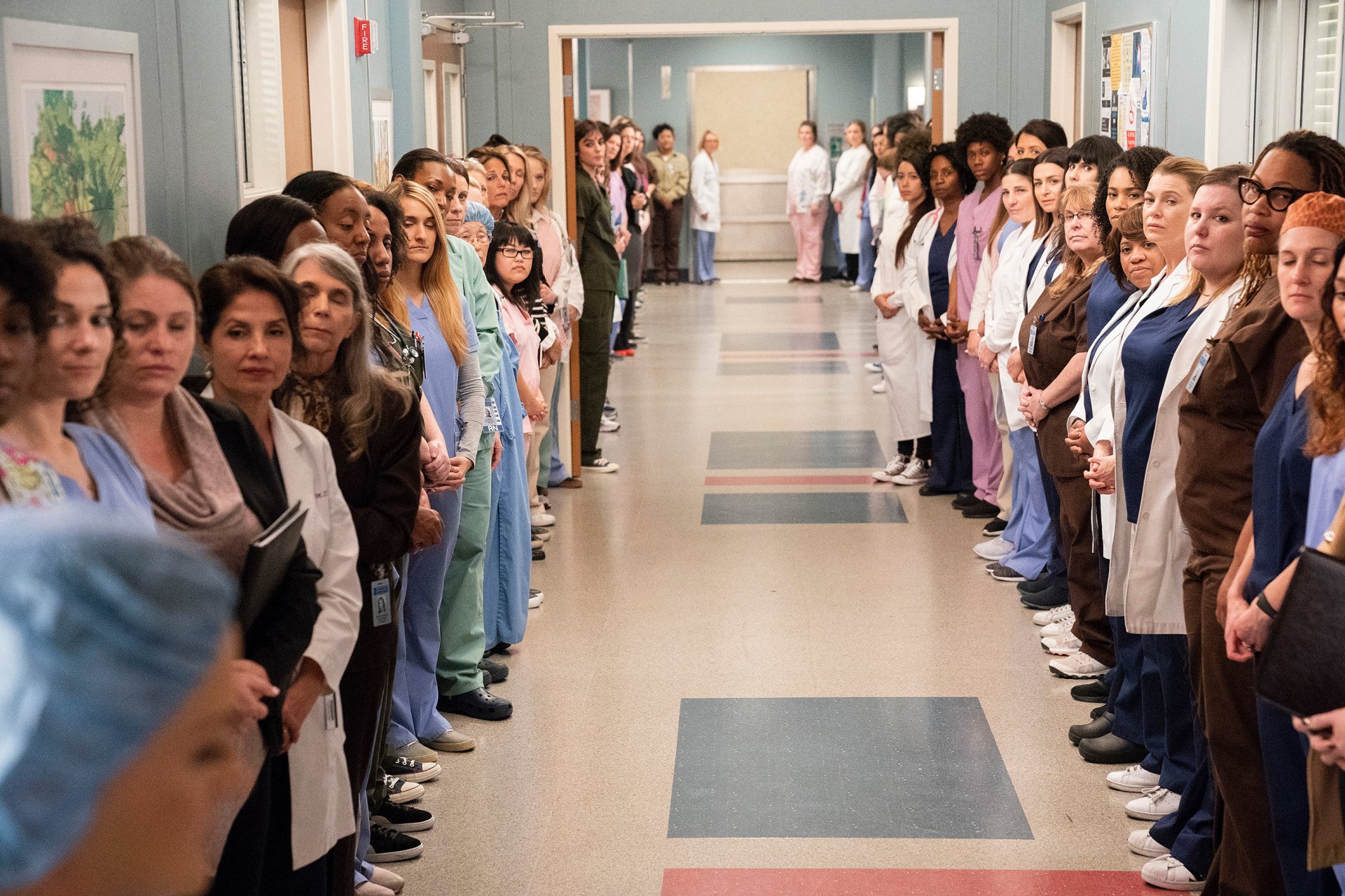 HD wallpaper of Grey's Anatomy with characters lining a hospital corridor, creating a background scene.