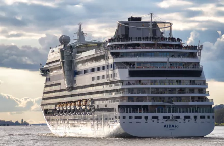 HD PC desktop wallpaper/background: AIDAsol cruise ship (vehicle) gliding through calm sea beneath a dramatic, cloud-filled sky.