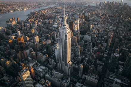 Aerial view of New York City featuring the Empire State Building towering over surrounding skyscrapers and cityscape at sunset.