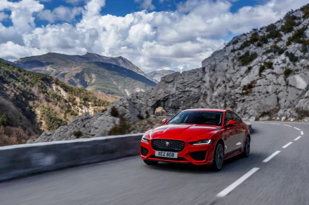 A red Jaguar XE car driving on a mountain road under a partly cloudy sky, showcased as a 4K Ultra HD PC desktop wallpaper and background.