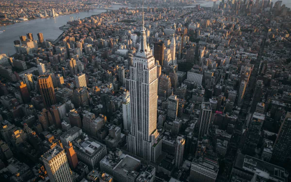 Aerial view of New York City featuring the Empire State Building towering over surrounding skyscrapers and cityscape at sunset.