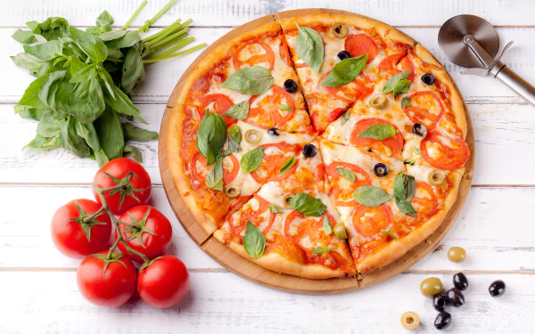 Still life HD PC desktop wallpaper/background: wood table with pizza topped with olives, tomato slices and basil; vine tomatoes and basil bunch alongside — appetizing food scene.