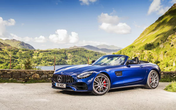 Blue Mercedes‑Benz AMG GT cabriolet car parked on a mountain road with green hills — sporty AMG vehicle featured as a 5K Ultra HD PC desktop wallpaper and background.