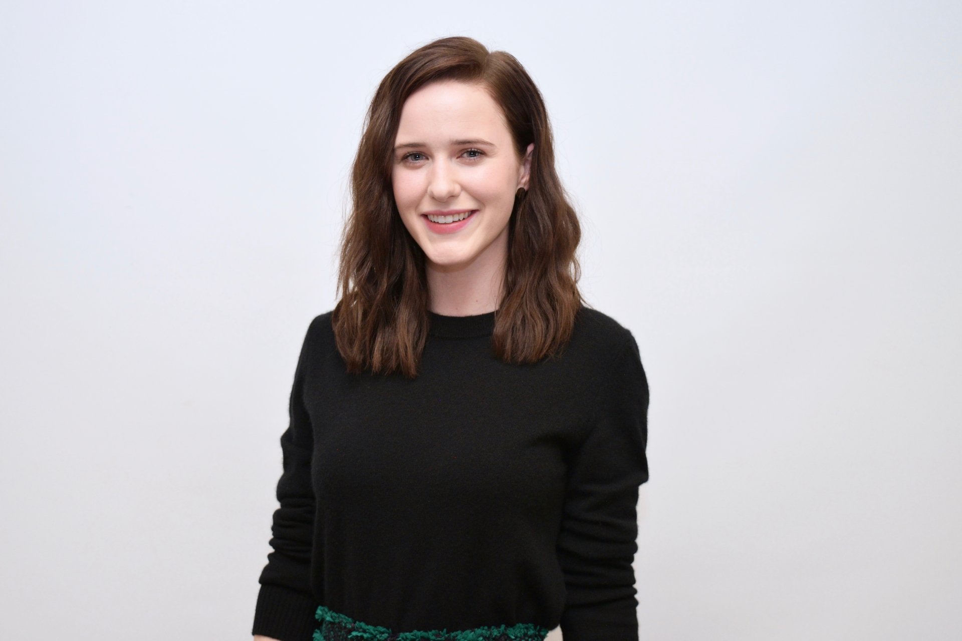 Smiling brunette American actress in a black top against a pale background — 5K Ultra HD PC desktop wallpaper/background.