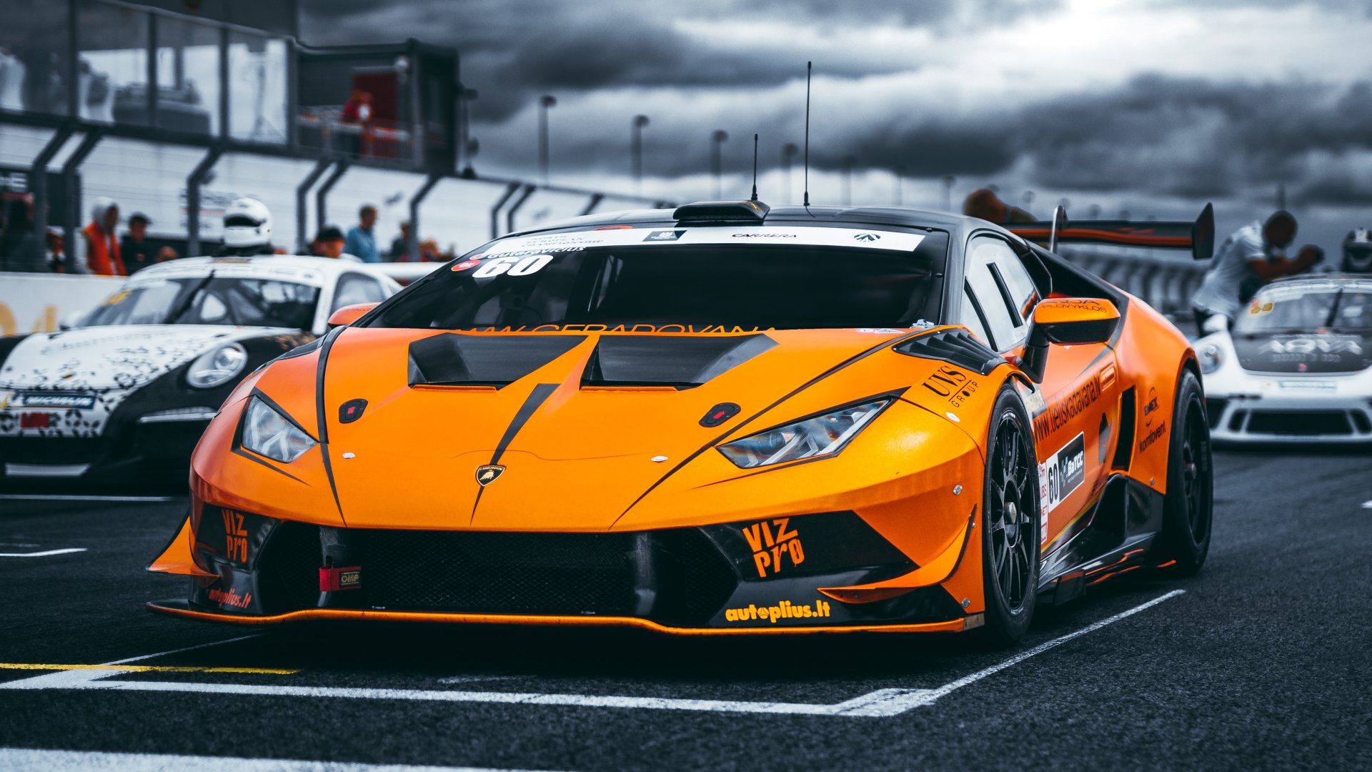 Orange Lamborghini Huracan race car on a racetrack under moody skies — 4K Ultra HD PC desktop wallpaper.