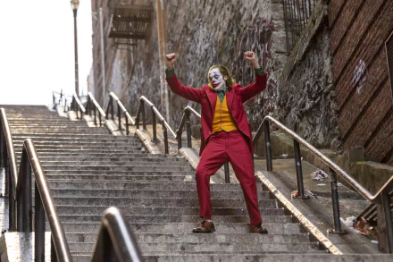 Joaquin Phoenix as Joker from DC Comics, captured mid-dance on urban stairs in a vibrant 4K Ultra HD movie wallpaper and desktop background.
