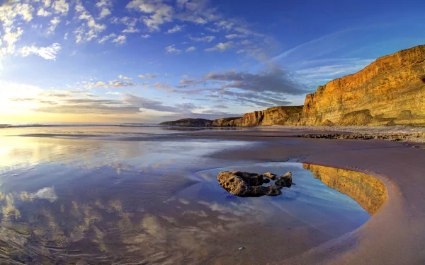 4K Ultra HD desktop wallpaper showing the Wales coastline with cliffs, ocean, beach, and a vivid horizon under a partly cloudy sky.
