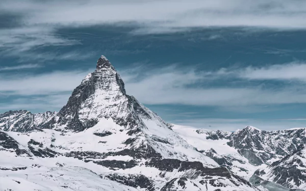 Snow-covered Matterhorn peak rises sharply against a cloudy sky in this stunning 4K Ultra HD winter mountain landscape.
