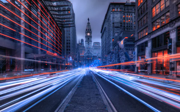 2K Quad HD PC desktop wallpaper and background: night time-lapse street photography in Philadelphia, Pennsylvania — light trails streak between buildings toward a distant civic tower.