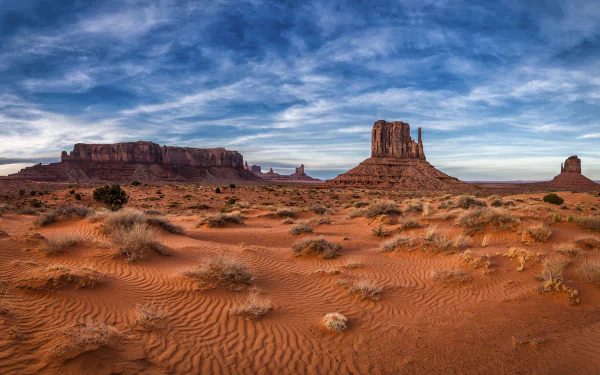 4K Ultra HD landscape of Monument Valley desert in the USA, showcasing red sand dunes under a dramatic sky as a stunning nature desktop wallpaper.