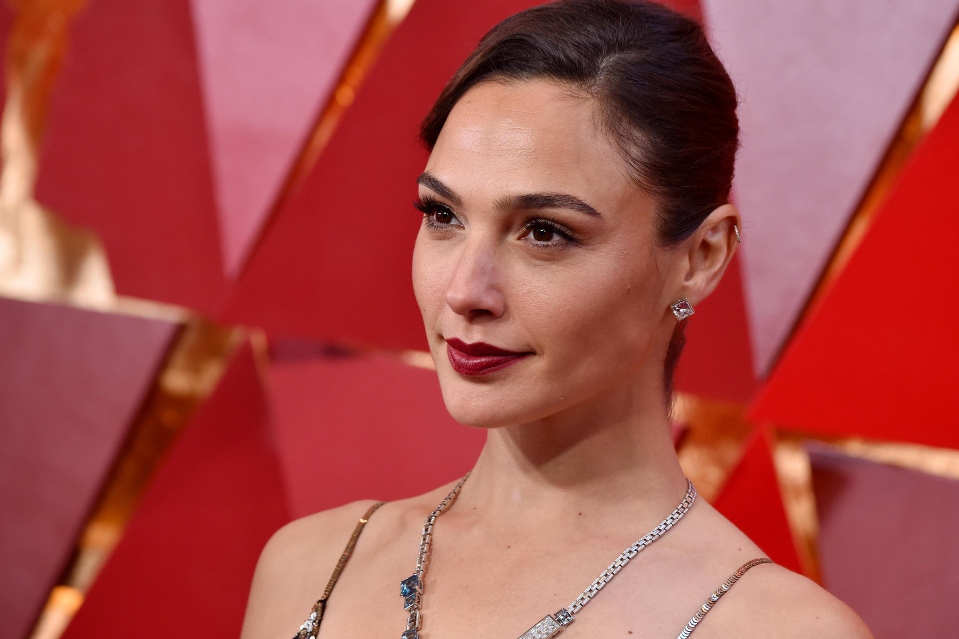 HD desktop wallpaper featuring Israeli actress and model Gal Gadot with black hair, brown eyes, and wearing bold lipstick at a red carpet event.