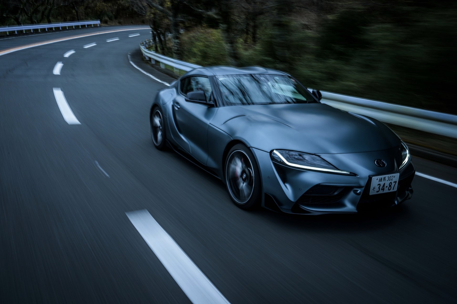 Silver Toyota GR Supra sports car leaning through a mountain curve, captured as a 4K Ultra HD PC desktop wallpaper background of a dynamic vehicle.