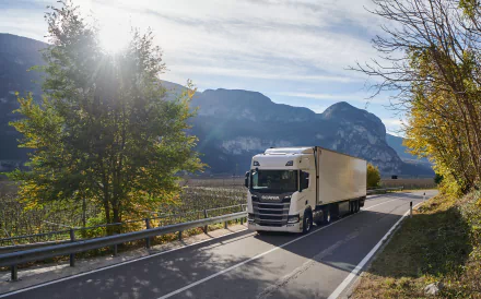 Scania R410 truck driving on a scenic road with mountains and trees, captured as an HD PC desktop wallpaper featuring the vehicle and natural landscape.