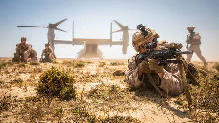 4K Ultra HD military wallpaper showing a soldier aiming a rifle while lying on desert terrain, with comrades and a tiltrotor aircraft in the background.