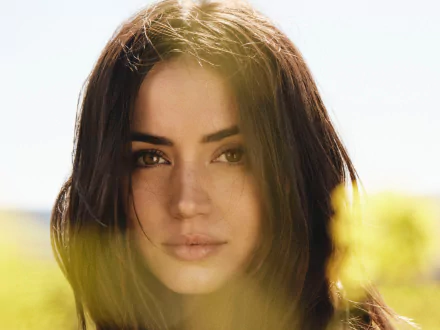 Close-up HD portrait of brunette Cuban actress Ana de Armas with soft natural lighting, capturing her face against a blurred outdoor background.