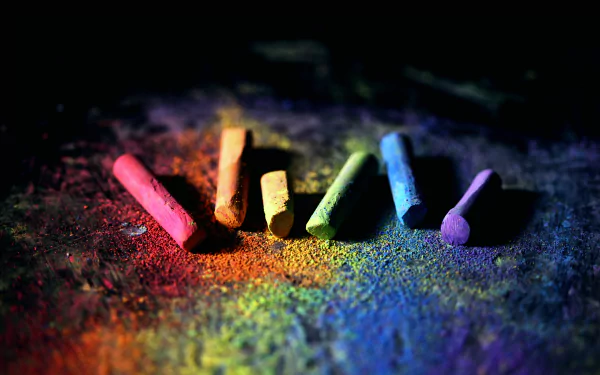 Close-up chalk photography: six vibrant chalk sticks and scattered pigments on a dark surface — 5K Ultra HD PC Desktop Wallpaper and Background.