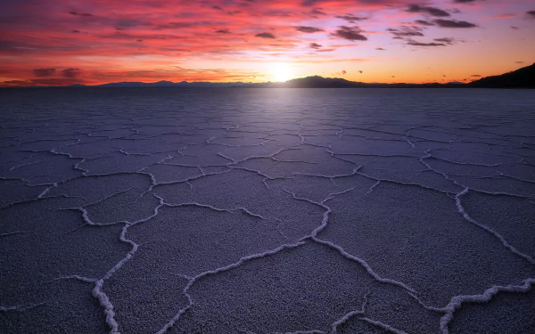 Nature scene - Utah desert landscape: cracked salt-flat foreground under a vivid sunrise sky, distant ridges on the horizon. HD PC desktop wallpaper/background.