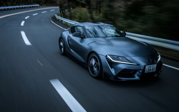 Silver Toyota GR Supra sports car leaning through a mountain curve, captured as a 4K Ultra HD PC desktop wallpaper background of a dynamic vehicle.