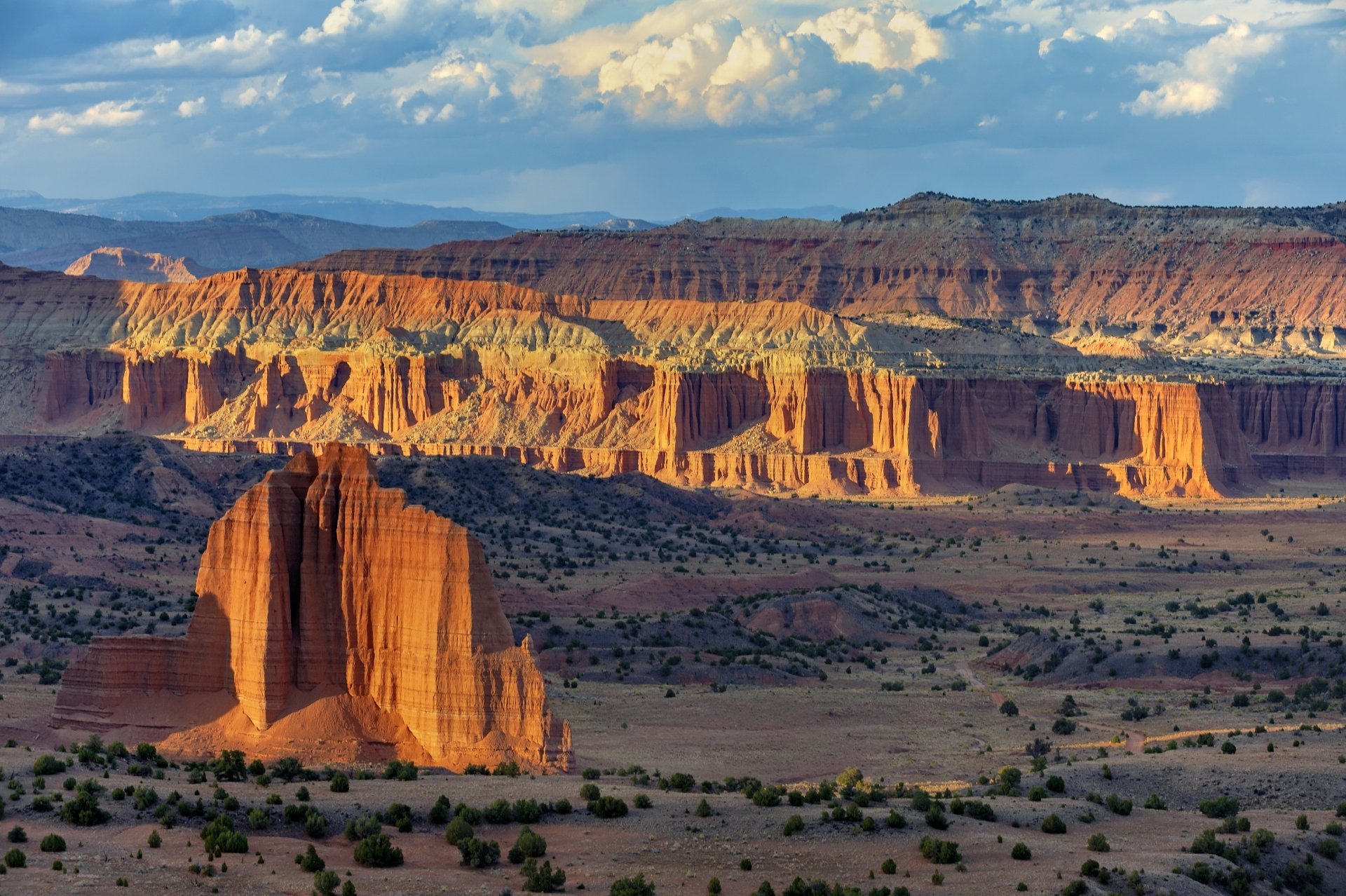 4K Ultra HD PC desktop wallpaper of a nature canyon: sunlit layered sandstone cliffs and a lone monolith under a blue sky.
