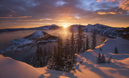 Sunbeam breaks through clouds over snowy Crater Lake in winter, with a vibrant sky illuminating the serene natural landscape.
