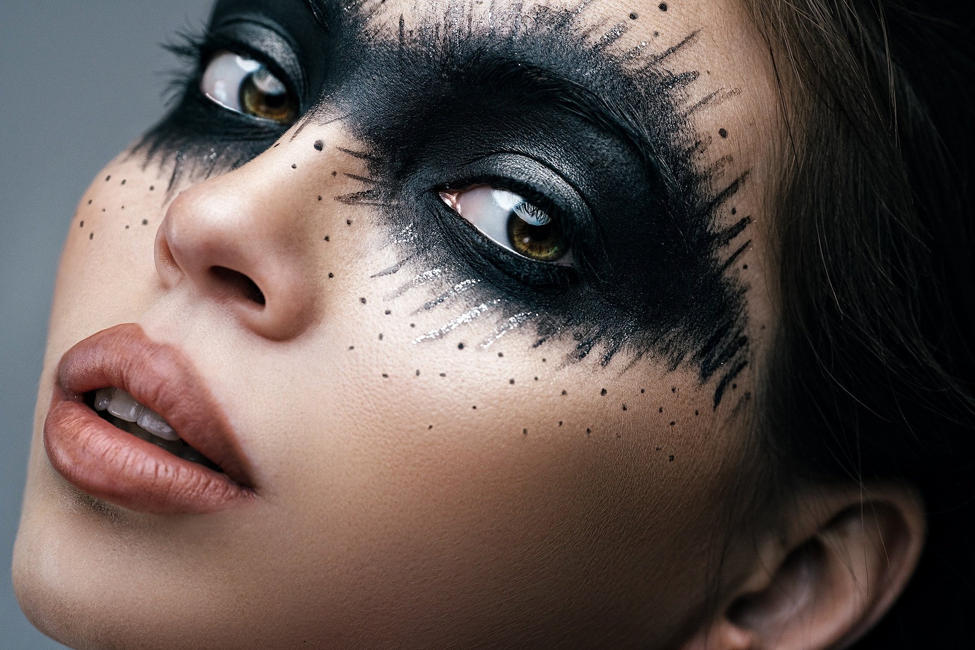 HD PC desktop wallpaper: close-up of a brunette model woman's face, dramatic black feathered eye makeup with speckled accents.