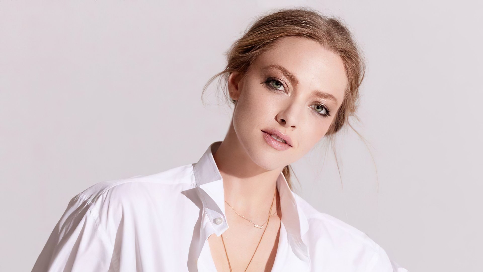 Close-up portrait of actress Amanda Seyfried with natural makeup, wearing a white shirt, presented as a 4K Ultra HD desktop wallpaper and background.