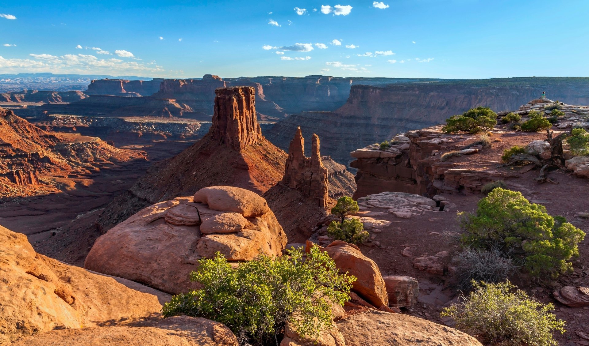 4K Ultra HD image of a stunning canyon landscape in the USA, showcasing rugged rock formations, deep valleys, and vibrant greenery under a bright blue sky.