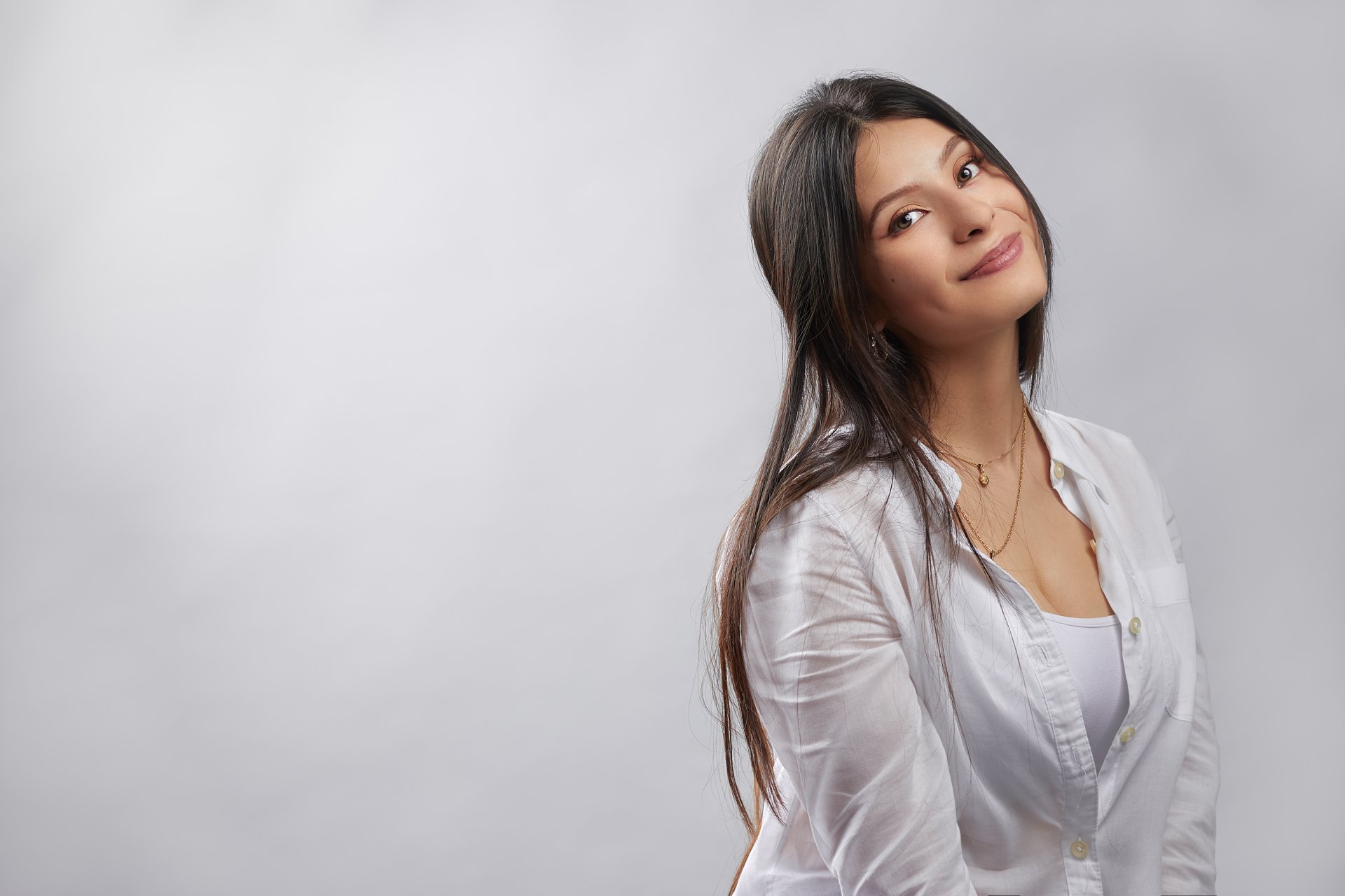 Long-haired woman model with black hair, smiling in a white blouse against a soft gray backdrop — 2K Quad HD PC desktop wallpaper/background.