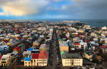 A vibrant cityscape of Reykjavik, Iceland, featuring colorful buildings and streets with the ocean in the background, captured in 4K Ultra HD for a desktop wallpaper.