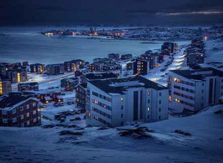 A snowy Greenland town at night under a winter sky, illuminated by streetlights and building windows, captured in stunning 4K Ultra HD resolution.