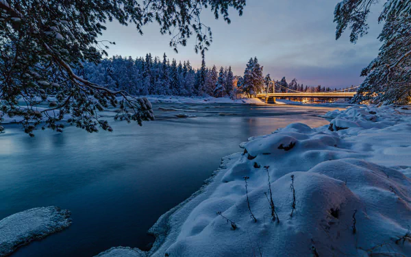 A serene winter night scene of a snow-covered forest and a man-made bridge over a calm river, captured in stunning 4K Ultra HD clarity.