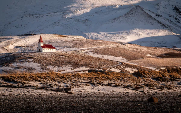 Víkurkirkja church stands amid Iceland’s rugged landscape, captured in stunning 4K Ultra HD with snow-dusted hills and dramatic light enhancing this religious site.