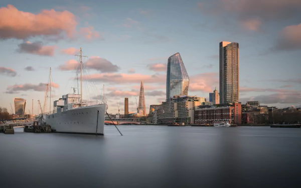 4K Ultra HD wallpaper of London’s skyline at sunset, featuring the Thames River with a ship and various vehicles against a colorful sky.