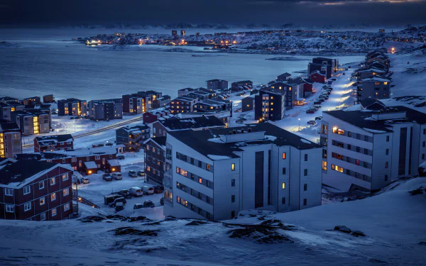 A snowy Greenland town at night under a winter sky, illuminated by streetlights and building windows, captured in stunning 4K Ultra HD resolution.