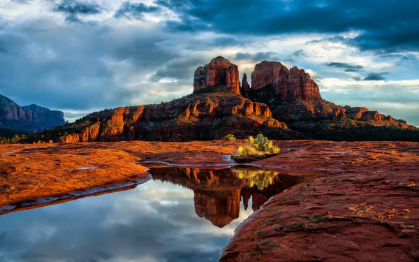 4K Ultra HD image of Sedona, Arizona desert canyon with dramatic clouds and sky reflected in a calm water pool, showcasing vibrant natural colors and rugged terrain.