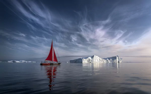 Sailboat with a red sail near a large iceberg in calm Arctic waters of Greenland under a dramatic sky, captured in HD for a desktop wallpaper background.