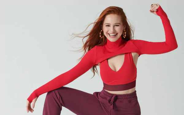 Redhead American actress Madelaine Petsch smiles confidently in a vibrant red outfit, captured in a sharp 4K Ultra HD desktop wallpaper.