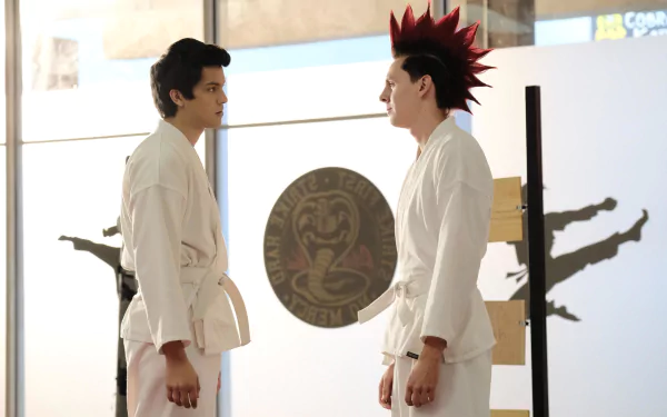 Eli (Cobra Kai) faces an opponent in white gi inside the Cobra Kai dojo, cobra emblem on the wall — 5K Ultra HD PC desktop wallpaper.