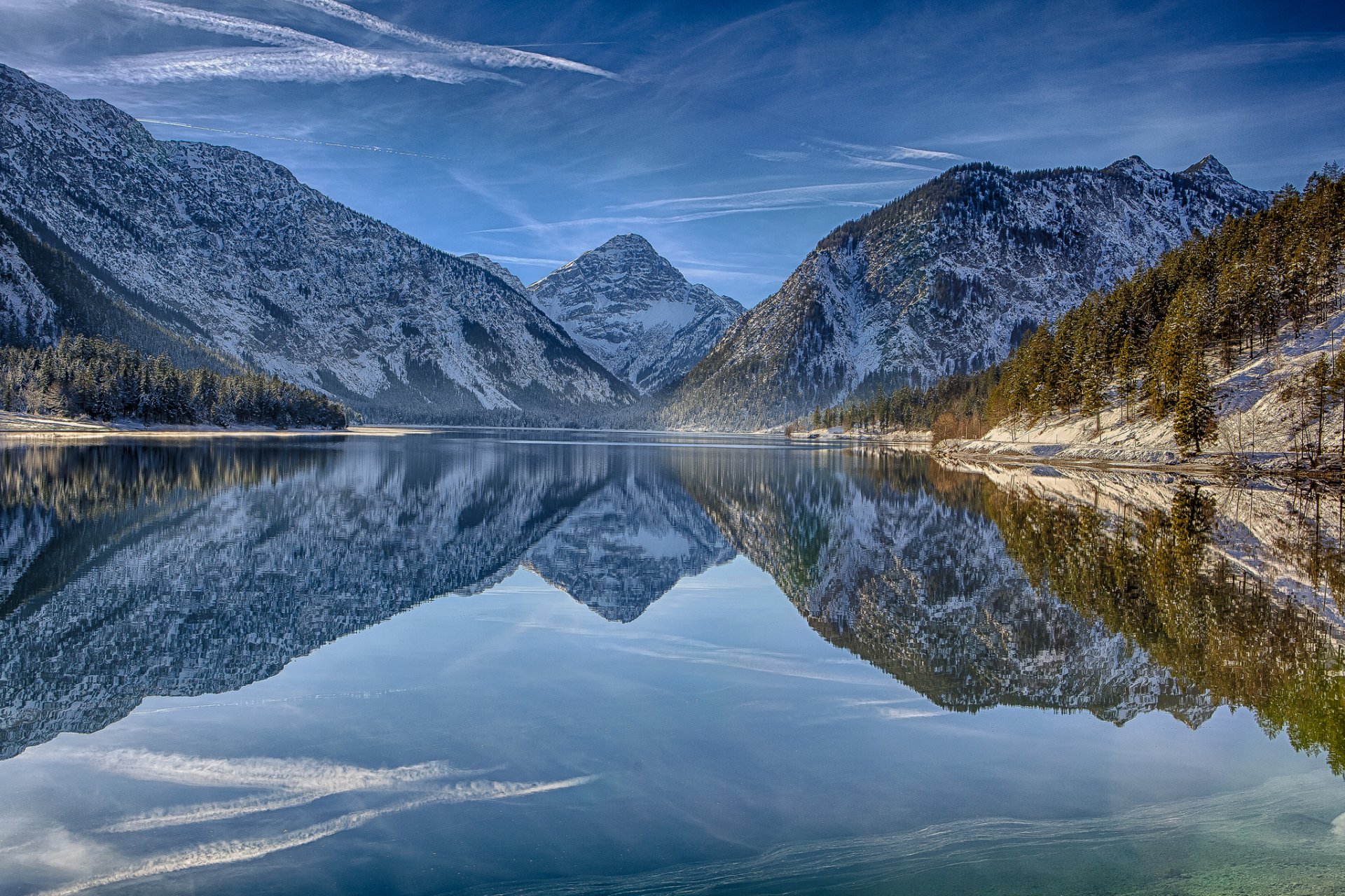 HD desktop wallpaper of Lake Plansee in Tirol, Austria, showcasing alpine mountains and their clear reflections on the tranquil lake surface in the heart of the Alps.