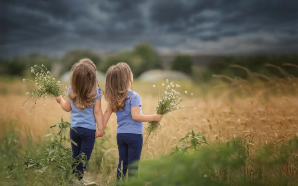  Twin Girls holding Flowers while Looking up at Dark Clouds