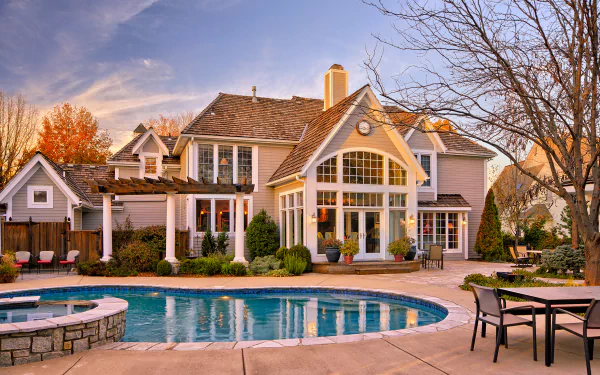 A spacious courtyard with a curved pool in front of a large, elegant house surrounded by autumn trees, captured in an HD PC desktop wallpaper.