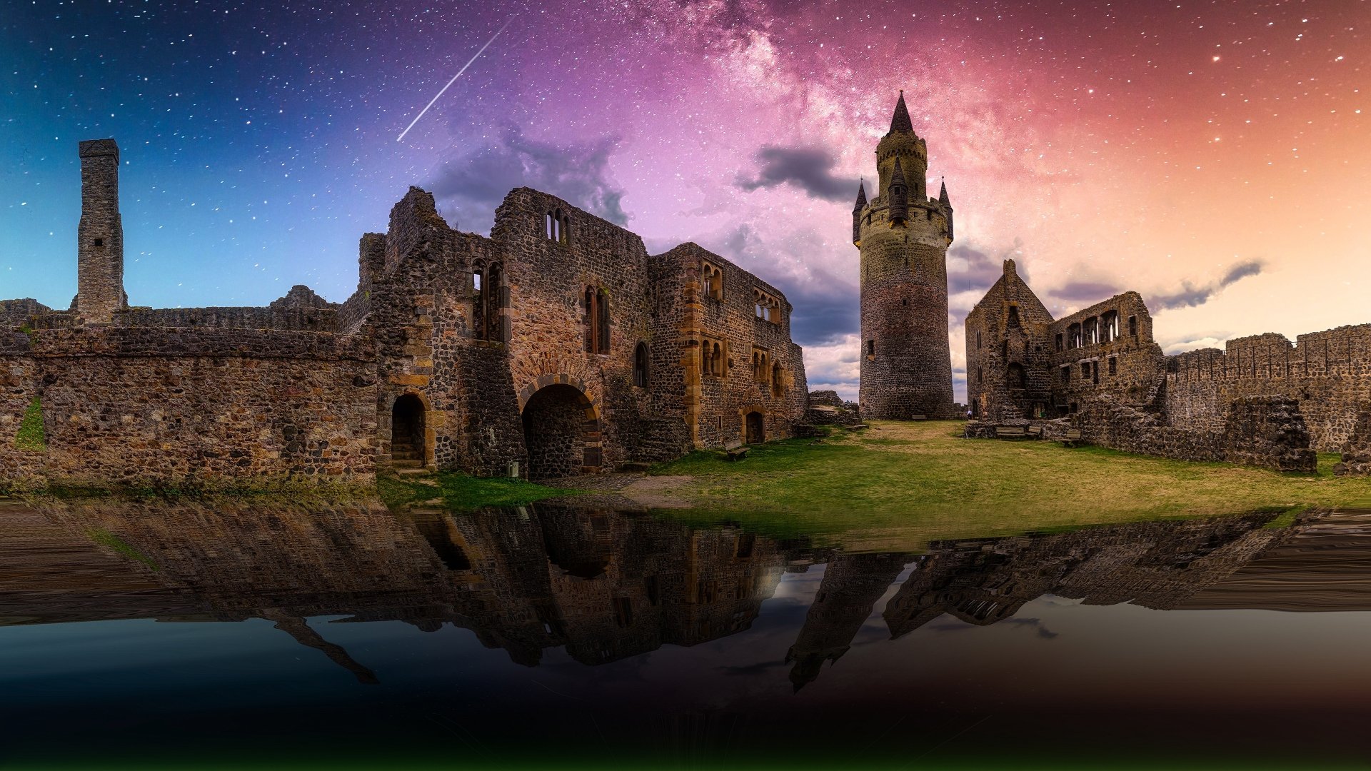 4K Ultra HD desktop wallpaper: man-made ruined stone fortress and castle at night beneath a starry, cloud-streaked sky with a shooting star, reflected in calm water.