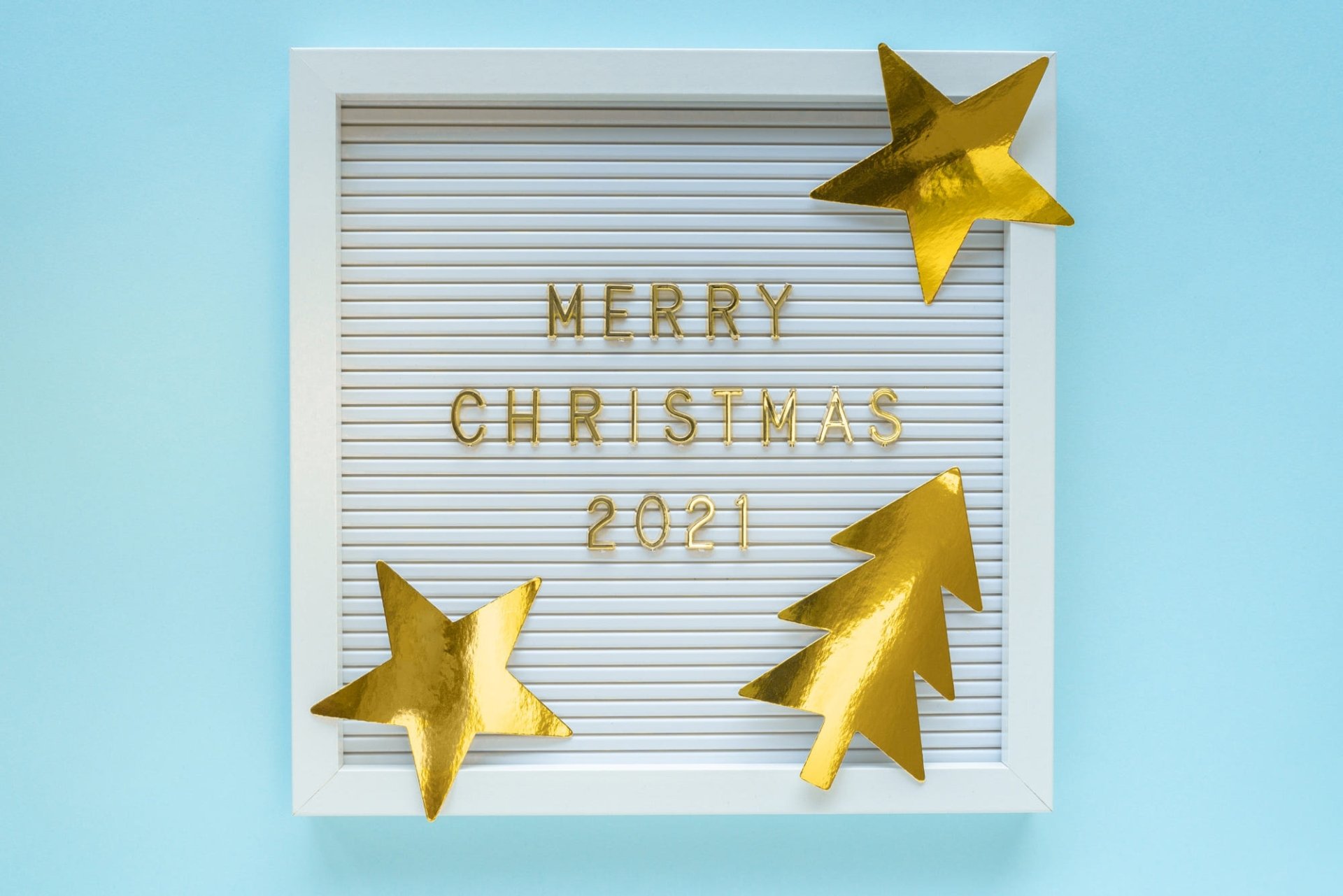 HD desktop wallpaper: white framed letterboard reading Merry Christmas 2021 with gold glitter stars and a tree on pale blue — holiday number-themed design.