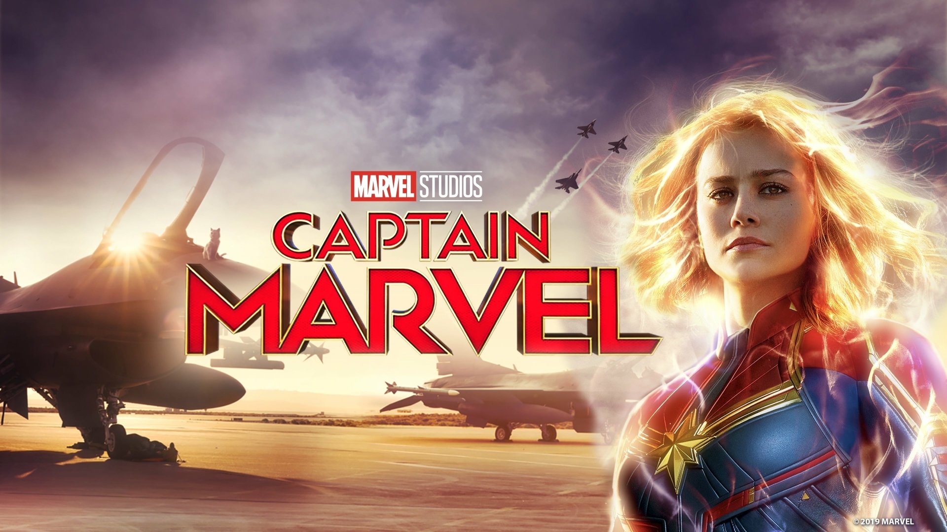 4K Ultra HD PC wallpaper of Captain Marvel (Carol Danvers) — glowing hero in her suit with jets on a sunset airfield, Marvel Studios title prominent in the sky.
