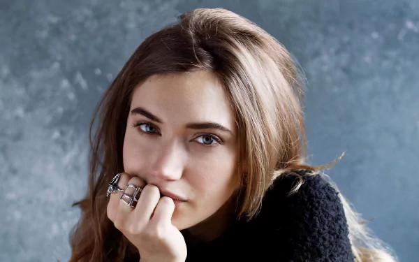 HD desktop wallpaper featuring brunette actress Imogen Poots, posing thoughtfully with her chin resting on her hand against a textured gray background.