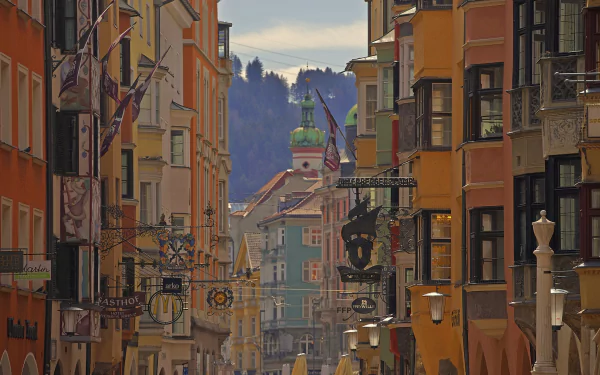 HD desktop wallpaper showcasing colorful man-made buildings and houses lining a street in Innsbruck, Austria, with mountain scenery in the background.