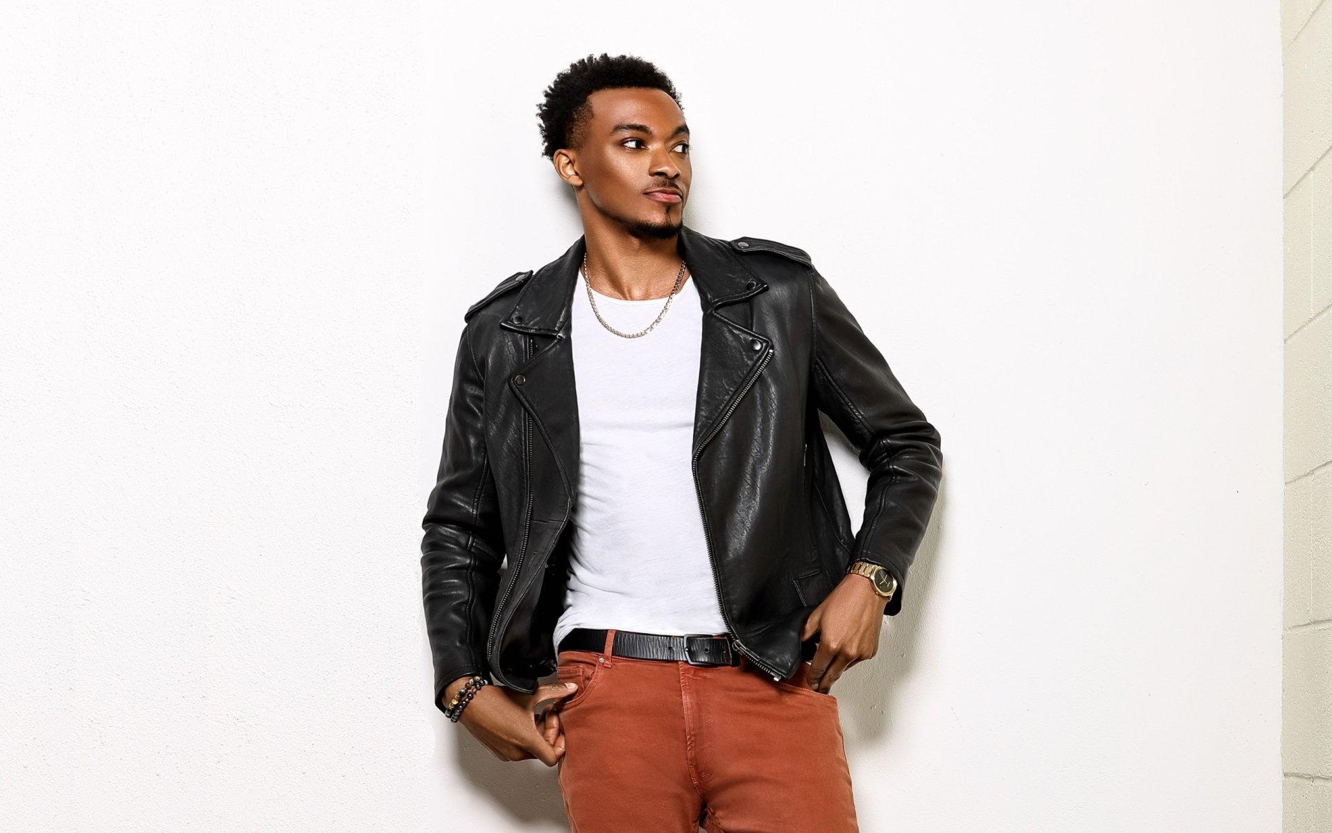HD desktop wallpaper of a stylish man in a black leather jacket and red pants, posing confidently against a white background.