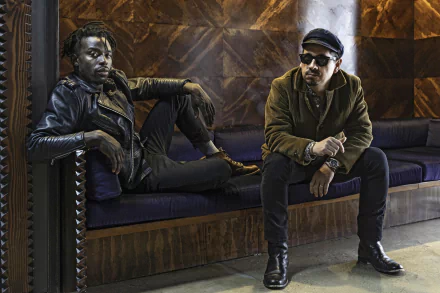 HD desktop wallpaper featuring two members of the Black Pumas band seated casually in a stylish interior setting.
