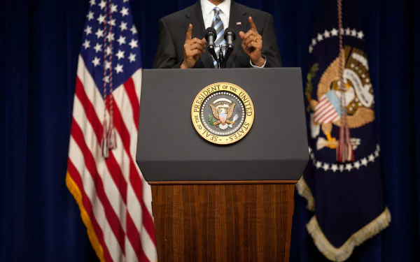 HD wallpaper featuring the White House seal on a podium with a person speaking, flanked by American flags.