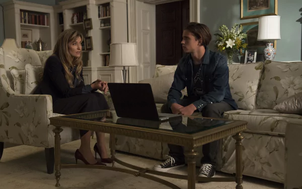 HD wallpaper featuring Tanner Buchanan and a co-star in a living room scene with a laptop on a coffee table.